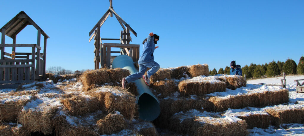 A boy playing on the holiday haystack play area at Hanns Christmas Farm.